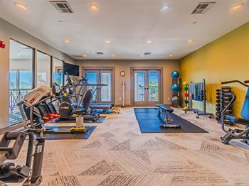 A well-equipped gym with a variety of exercise machines and a blue mat for floor exercises.